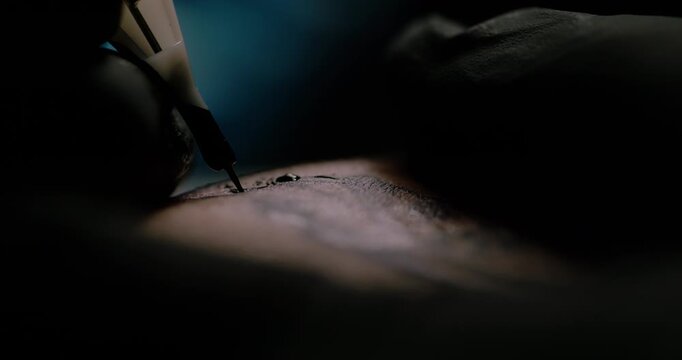 Fine line tattoo detailing with tattoo machine in slow motion