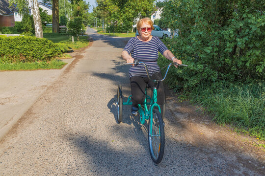 Retired woman ride bicycle on sunny suburban street