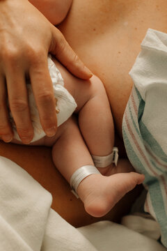 Tiny feet of a newborn baby being held by her mother's hand.