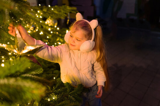 Girl decorate Christmas tree with a star ornament