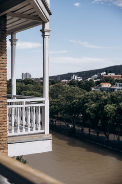White veranda overlooking riverside city and green hillside