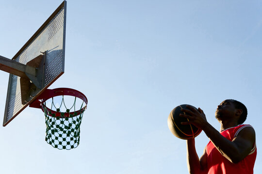 Player Shoots Basketball Towards Hoop During Evening Practice Session