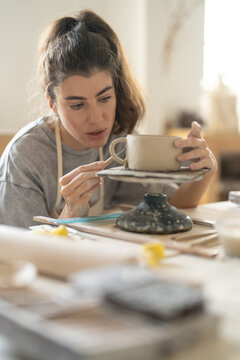 Ceramic artist examining handmade clay cup
