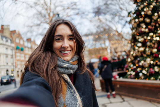 Smiling woman taking selfie by Christmas tree in London