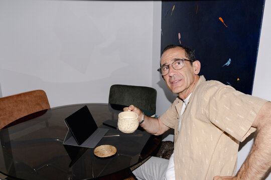 Senior man having coffee with tablet and pet dog at home dining table
