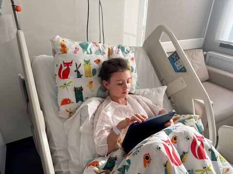 Child use tablet in hospital bed during recovery