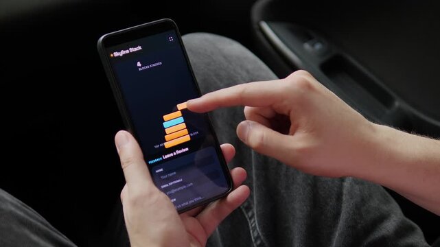 A passenger plays a minimalist stacking game on a smartphone in a parked car, capturing the rise of casual mobile entertainment, screen-time habits and on-the-go digital leisure.