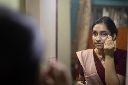 Young Indian woman doing self make up inside home