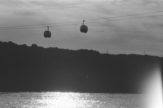 Cable cars travel across the water with hills in the background