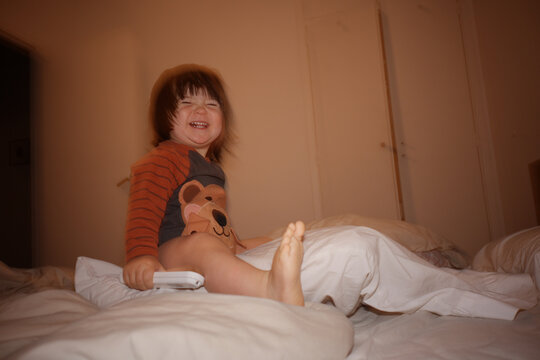 Child Plays on Bed and Smiles in a Room During NIghttime