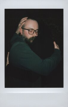Man with Glasses and Beard Hugging Partner, Instant Film Snapshot