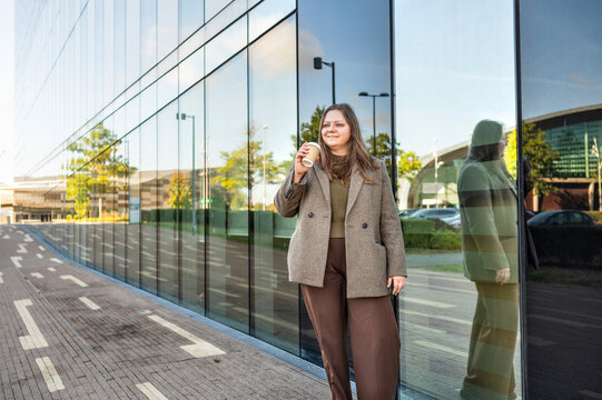 Businesswoman with coffee outside modern office building