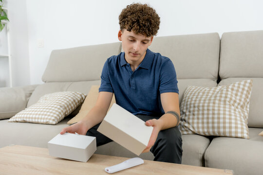 Young man unboxing a white product package at home