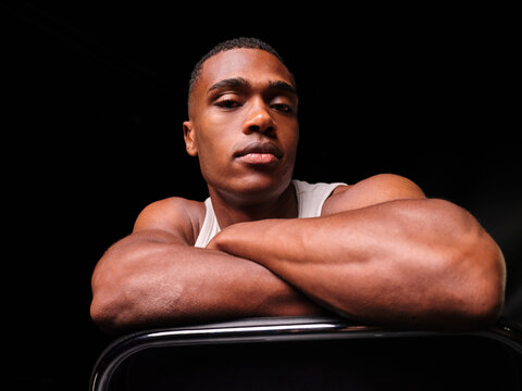 Determined muscular man resting arms on chair back