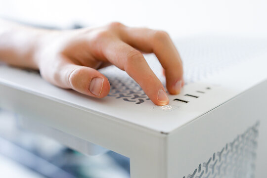 Hand operate button on a white gaming computer