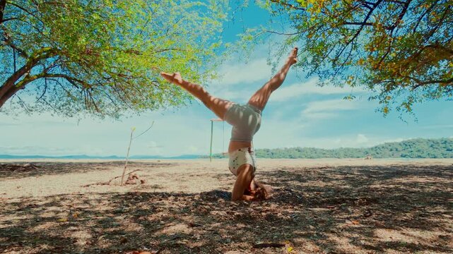 Woman performing yoga headstand and asanas on a beach