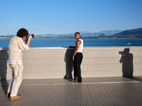 Photographer shooting male model posing by the sea