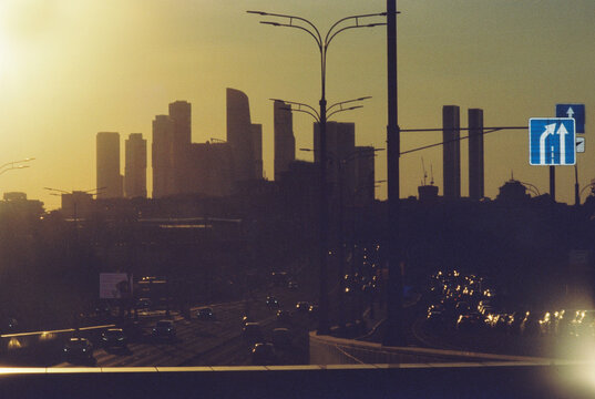 Sunset view of a city skyline with tall buildings and traffic on a bus