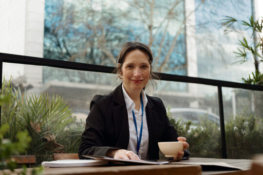 Woman Sits at a Table With a Cup in a Cafe Setting