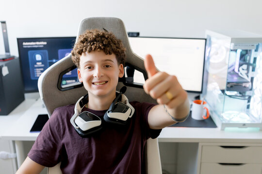 Young gamer with headset gives thumbs up at computer