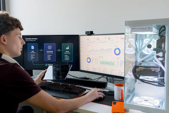 Young man using AI tools on dual monitor computer