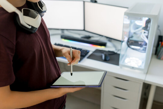Young man use tablet with stylus at gaming computer