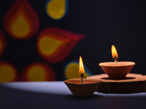 Two clay diyas with flickering flames illuminate a dark