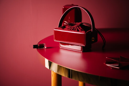 Red Leather Handbag And Nail Polish On Table