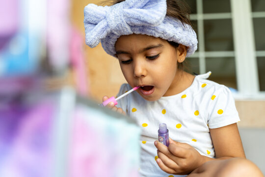 Girl Concentrating While Applying Gloss