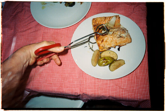 Person Using Tongs to Pick up Food From a Plate at Dinner