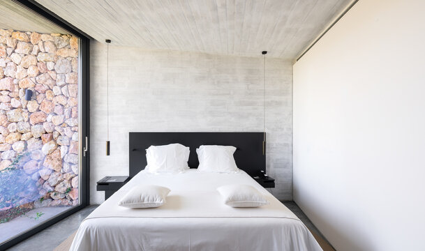 Minimalist luxury villa bedroom with stone wall in Catalonia