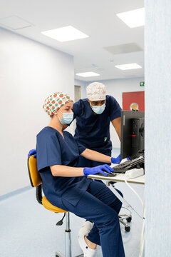 Medical team collaborating on computer in hospital hallway