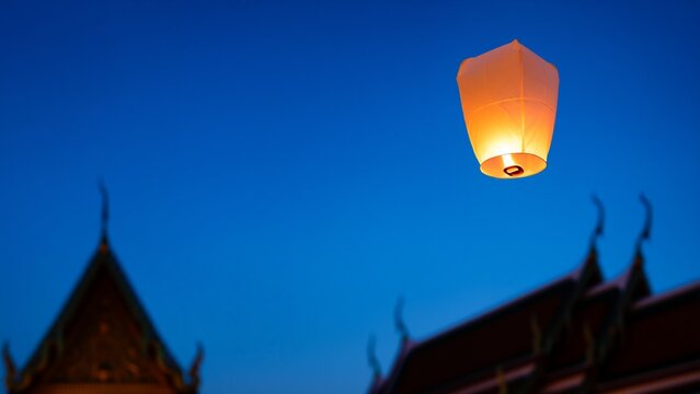 Yi peng lanterns glowing over temple dusk