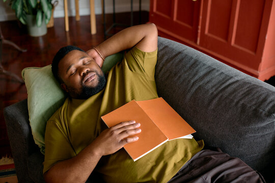 Man Resting on a Couch With a Book