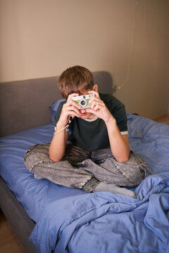Teen boy holding vintage film camera looking at viewfinder