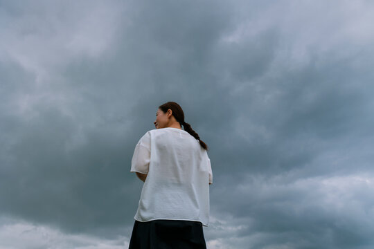 Facing the Storm: Woman Standing on the Coast