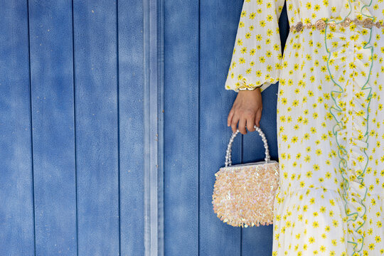 Woman in floral dress holding handbag outdoors