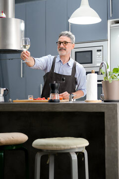Mature man cook and toast with wine in modern kitchen