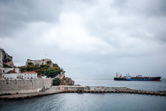 Cargo ship near Gibraltar waterfront under cloudy sky