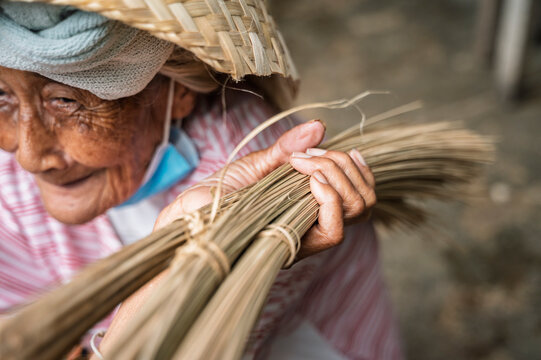 Elderly Balinese woman weaving palm leaves by hand