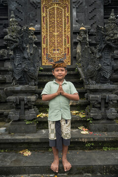 Balinese boy pray before ornate Hindu temple gate
