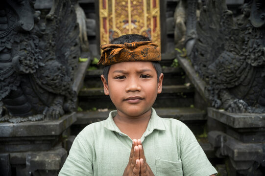 Balinese boy praying at traditional Hindu temple entrance