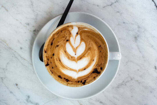 Latte art coffee in cup on marble table for breakfast