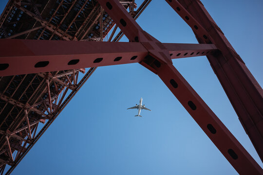 Airplane beneath red steel bridge in Porto, Portugal