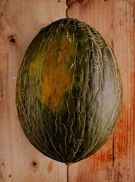 Dark green melon on rustic wood background, close-up