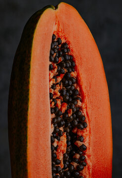 Close-up of ripe papaya half with black seed on dark