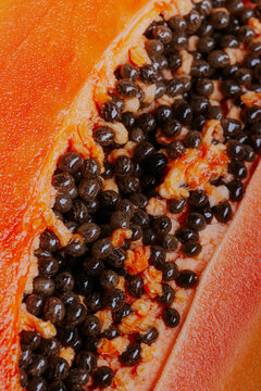 Macro view of ripe papaya slice with glossy black seed