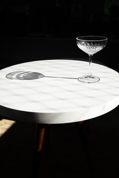 Empty cocktail glass on marble table in dark studio