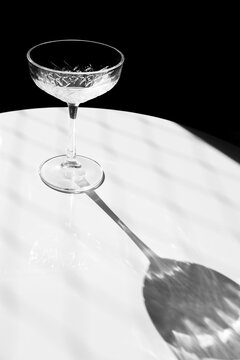 Empty cocktail glass casting long shadow on marble table