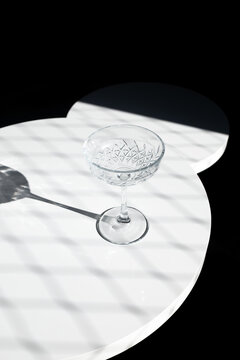 Empty cocktail glass on marble table in dark studio